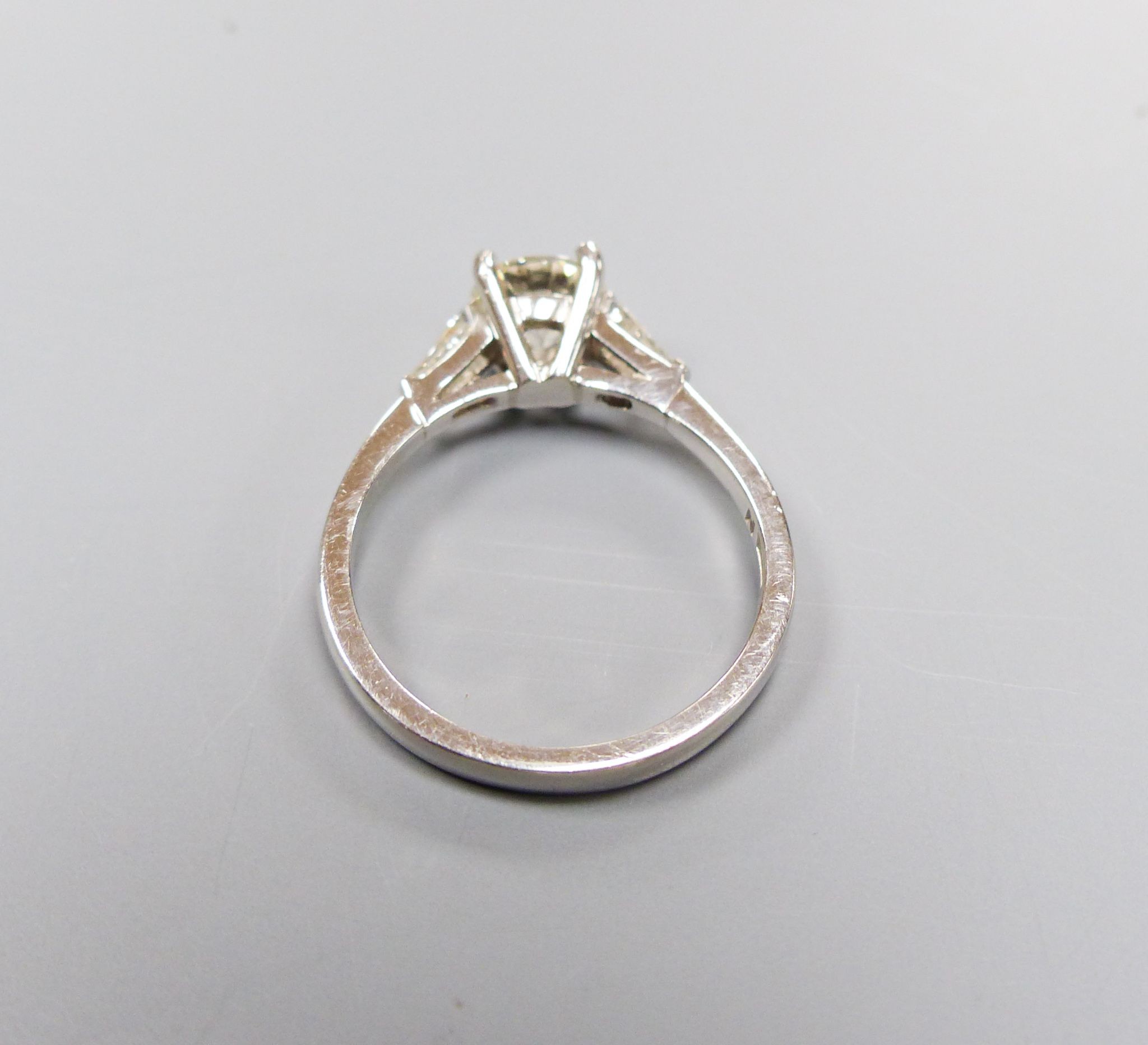 A modern platinum and single stone diamond ring, with trapeze cut diamond set shoulders, size N, gross weight 4.8 grams